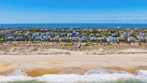 An aerial view of a coastal residential area with houses, a beach, and a clear sky. - Oceanfront Dog Friendly Home w/ Saltwater Pool, Elevator, Hot Tub, Cmty Perks (Waves)