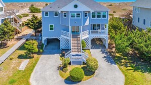 A two-story house with a front porch, a garage, and a view of the beach. - Oceanfront Dog Friendly Home w/ Saltwater Pool, Elevator, Hot Tub, Cmty Perks (Waves)
