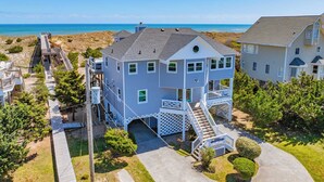 A two-story house with a balcony, a staircase, and a view of the ocean. - Oceanfront Dog Friendly Home w/ Saltwater Pool, Elevator, Hot Tub, Cmty Perks (Waves)