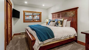 Una camera da letto con un letto di legno, una finestra che offre vista su un edificio e un televisore a schermo piatto montato a parete.