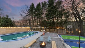 A backyard with a swimming pool, a fire pit, outdoor seating, and a tennis court. - Splash House - Heated Pool, Hot Tub, Pickleball, Movie Theater (Asheville)