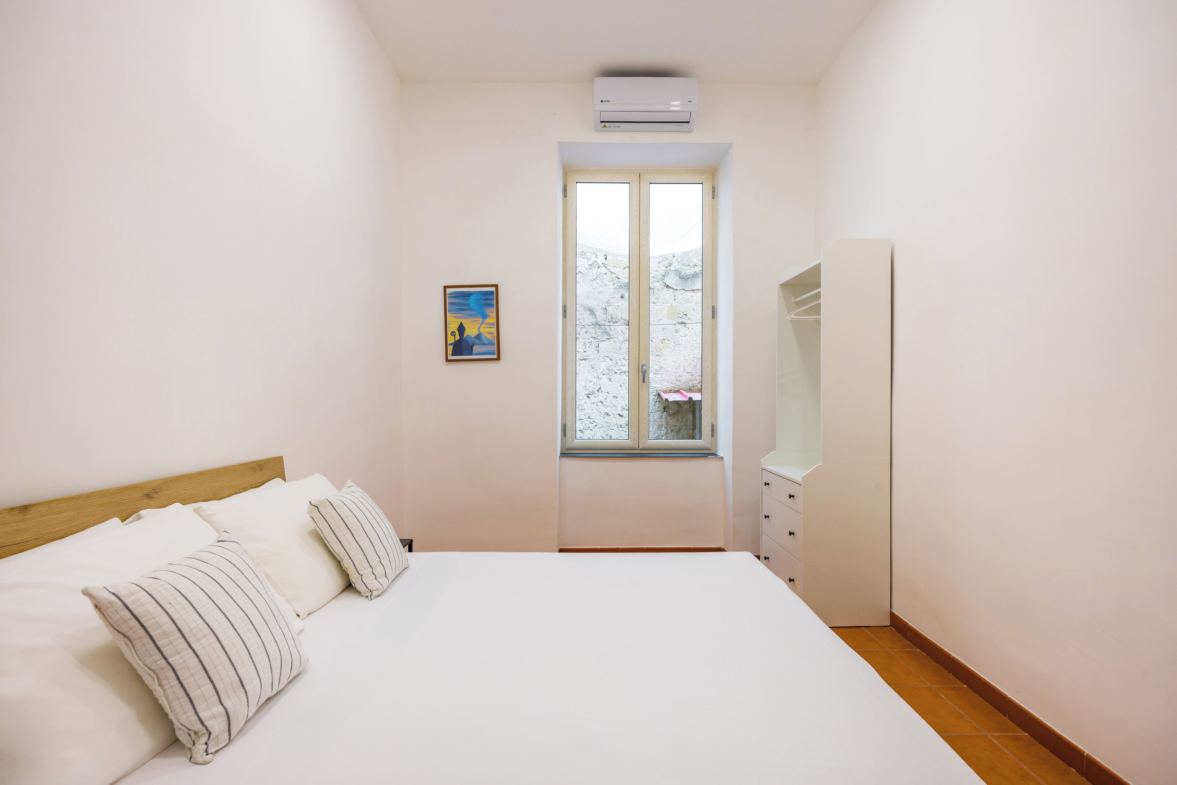 Une chambre à coucher avec un lit, une fenêtre, une armoire et un climatiseur.