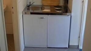 Une cuisine de taille réduite avec des meubles blancs, un plan de travail en bois et un évier.