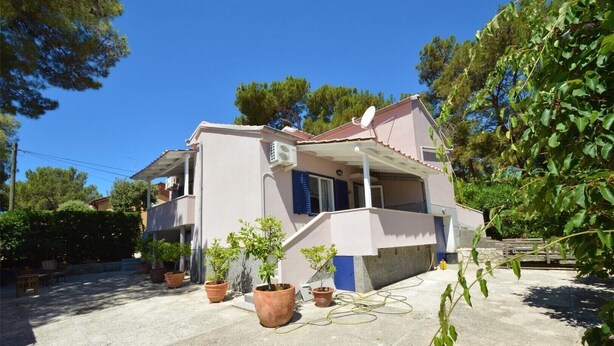 Une maison à deux étages avec un balcon, des plantes en pot et une antenne parabolique.