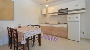 Een kleine keuken met witte kasten, een gasfornuis en een witte koelkast.