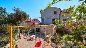 Un jardin avec une balançoire, une table et un banc.