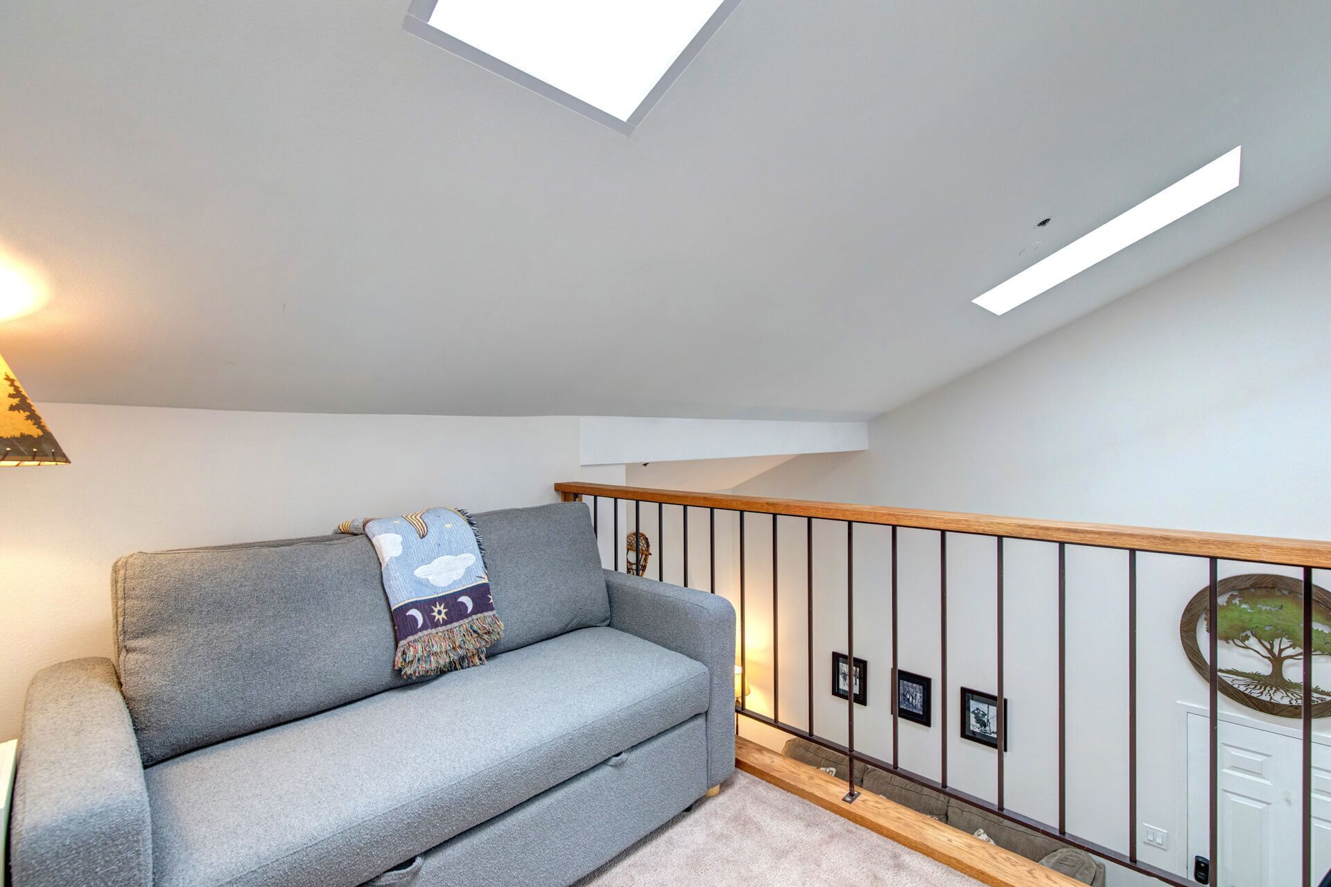Una sala de estar moderna con un sofá gris, techo de madera y una escalera con barandilla de madera.