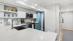 A modern kitchen with white cabinetry, a stainless steel microwave, and a built-in oven.