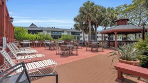 An outdoor patio with multiple barbecue grills, lounge chairs, and tables.