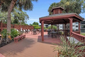 An outdoor patio area with wooden deck, lounge chairs, and a covered seating area. - H-248 - Luxury Corner Unit - Updated with Views (Naples)