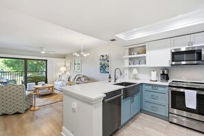 A modern kitchen with a central island, stainless steel appliances, and a view to the outside.