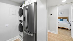 A compact kitchen with a stainless steel refrigerator, a washing machine, and a microwave.