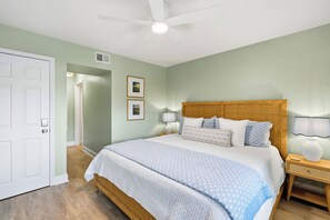 A bedroom with a bed, bedside lamps, a ceiling fan, and a door. - H-248 - Luxury Corner Unit - Updated with Views (Naples)