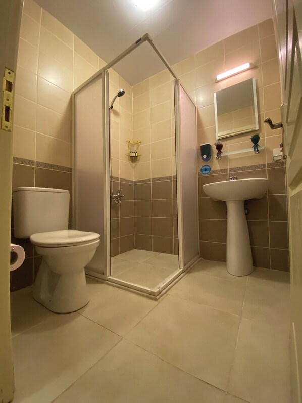 A bathroom with a toilet, a shower enclosure, and a sink. - Teras Otel Gökçeada (Gökçeada)