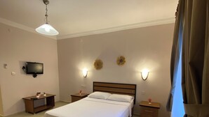 Un dormitorio con cama, mesitas de noche, televisor, apliques de pared y una lámpara de techo.