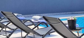 A poolside area with lounge chairs and a table with a drink dispenser. - Modern Home With Swimming Pool and sea View (Crikvenica)