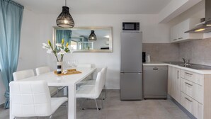 Una cucina moderna con frigorifero, microonde ed elettrodomestici. C'è un tavolo da pranzo con sedie e un vaso con fiori.