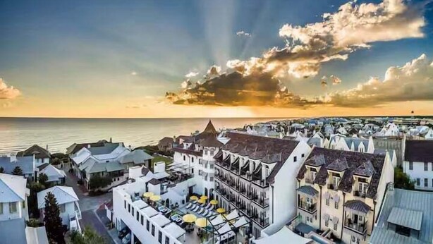 Un pueblo costero con edificios blancos, un paseo marítimo y una puesta de sol.