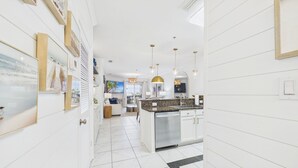 Una cocina moderna con una isla central, iluminación colgante y vistas al área de estar.