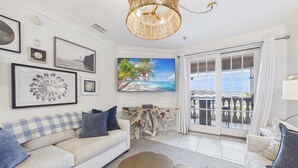 Una sala de estar con un sofá, una mesa de centro y un cuadro de una playa.