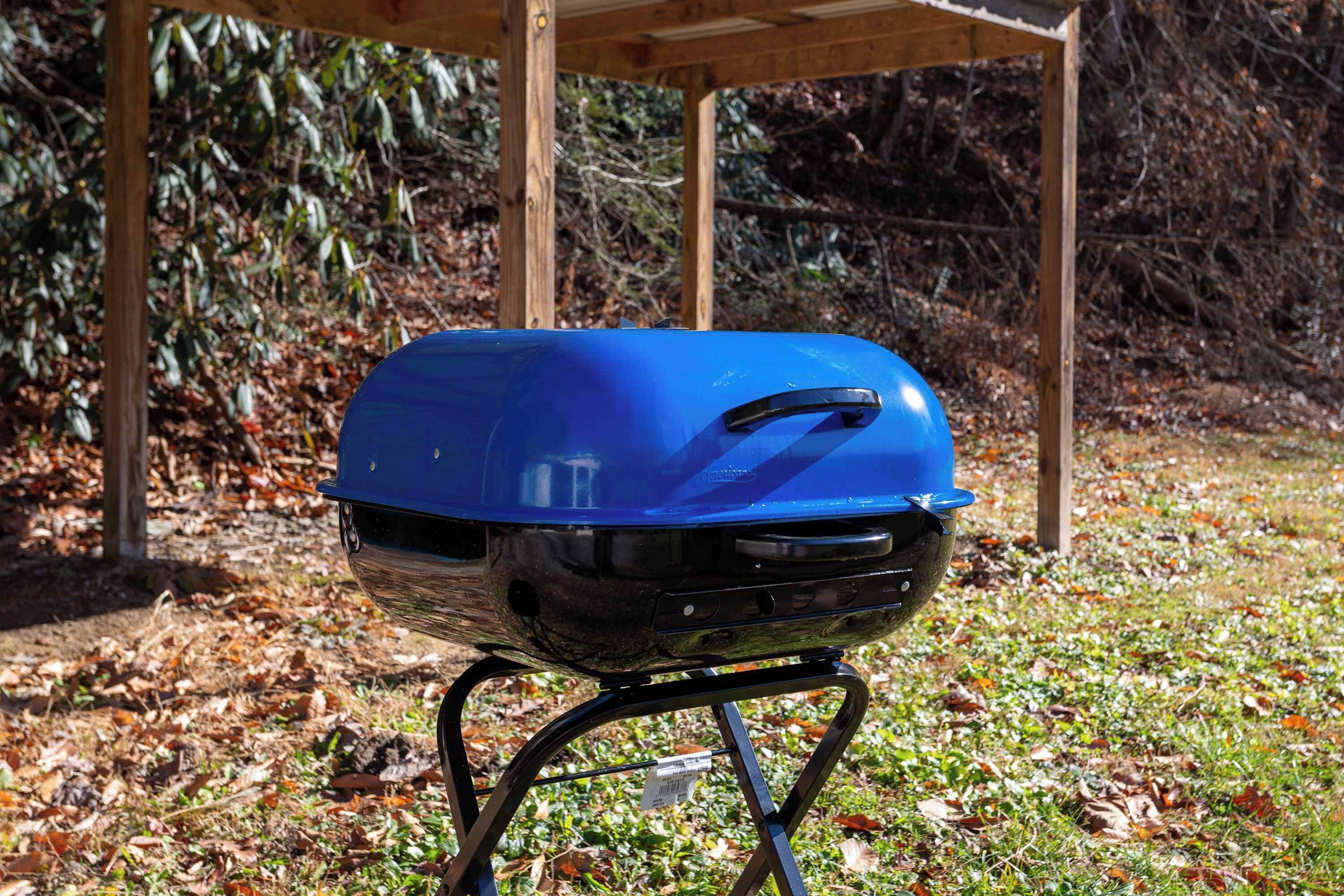 Una parrilla azul sobre un soporte en un área boscosa.
