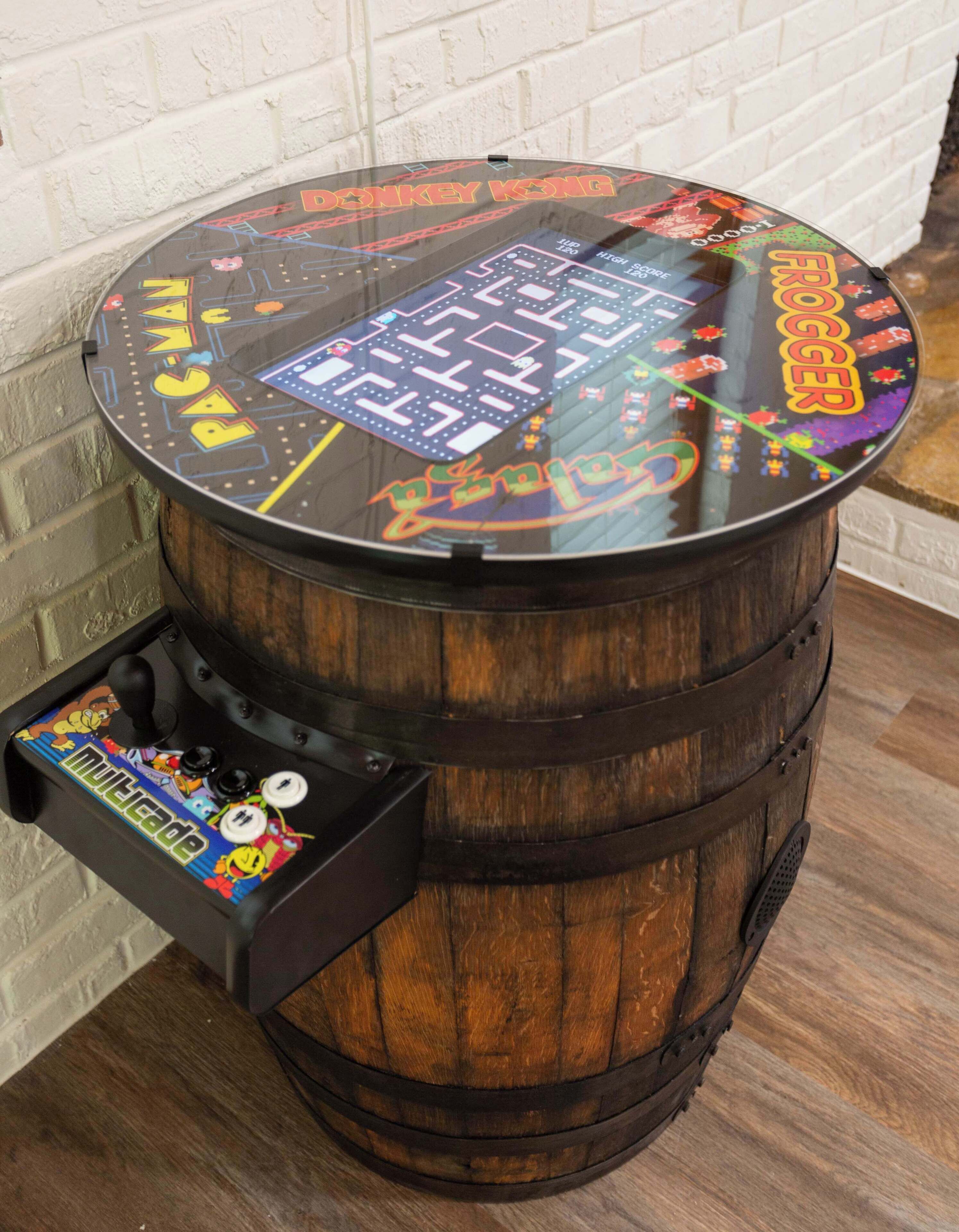 Une barrique en bois surmontée d’une borne d’arcade rétro, avec des graphismes colorés et les inscriptions « DONKEY KONG » et « Rocker ».