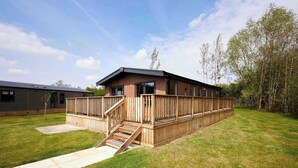 A modern wooden cabin with a deck, a staircase, and a clear view of the surrounding greenery. - Host & Stay | Linden Lodge, Ashdown Retreat (Pickering)
