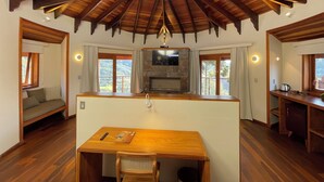 Une pièce spacieuse avec un plafond en bois, une cheminée centrale, une table à manger et un coin salon avec un canapé.