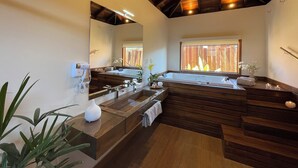 Une salle de bain moderne avec un grand miroir, deux lavabos, une baignoire et une fenêtre donnant sur une clôture en bois.
