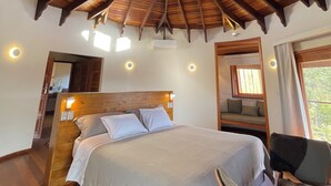 Une chambre avec un plafond en bois, un lit, une chaise et une fenêtre.