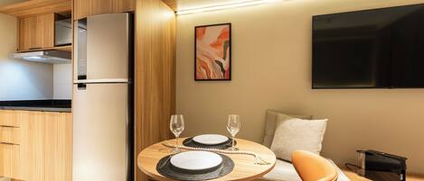 A compact kitchen with a refrigerator, wooden cabinets, and a dining area with a table set for two.