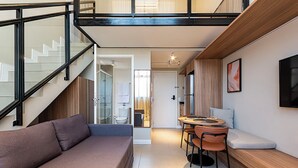 A modern interior with a staircase, a sofa, a dining area, and a kitchen. - Lexy Hotel (São Paulo)