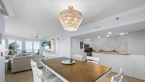 Une cuisine moderne avec des meubles blancs, une table à manger en bois et un lustre.