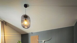 En moderne stue med en mørkegrøn sofa, et sofabord, et juletræ og en usædvanlig vægmonteret lampe.