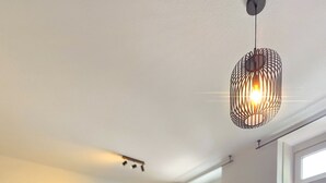 Et moderne soveværelse med en stor seng, et spiseområde og et køkken i baggrunden.