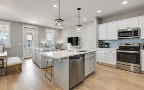 A modern kitchen with white cabinetry, stainless steel appliances, and a central island with a dishwasher.