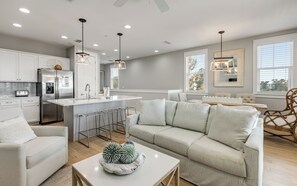 A modern kitchen with a central island, bar stools, and pendant lighting.