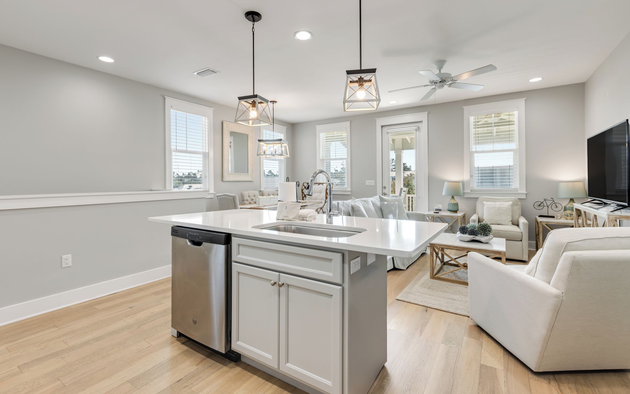 A modern kitchen with a central island, built-in dishwasher, and pendant lighting.