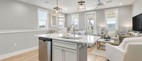 A modern kitchen with a central island, built-in dishwasher, and pendant lighting.