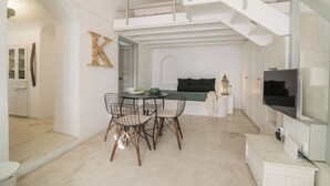 A modern interior with a dining area, a staircase, and a TV. - Kampanario Luxury Villa (Thira - Santorini)