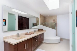 Bathroom features a large mirror, double sink vanity, and standalone bathtub.