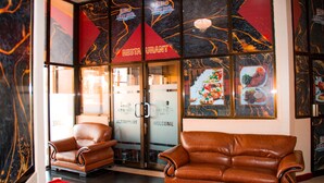 A lobby with leather armchairs, a red carpet, and a wall with 'Lenny Hotel' signage and a 'Restaurant' sign. - Lenny Hotel Ltd. (Geita)