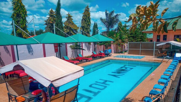 A swimming pool with 'LOH AMST' written on the water, surrounded by lounge chairs and umbrellas. - Lenny Hotel Ltd. (Geita)