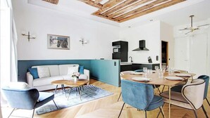 Una sala de estar moderna con un sofá, una mesa de comedor para cuatro comensales y una cocina al fondo.