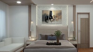 A modern bedroom with a large bed, a bedside table with a lamp, a decorative vase, and a painting of horses on the wall. - Villa Euphoria (Ootacamund)