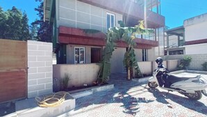 A two-story building with a tiled exterior, a motorcycle parked in front, and a garden area with a large plant. - Villa Euphoria (Ootacamund)