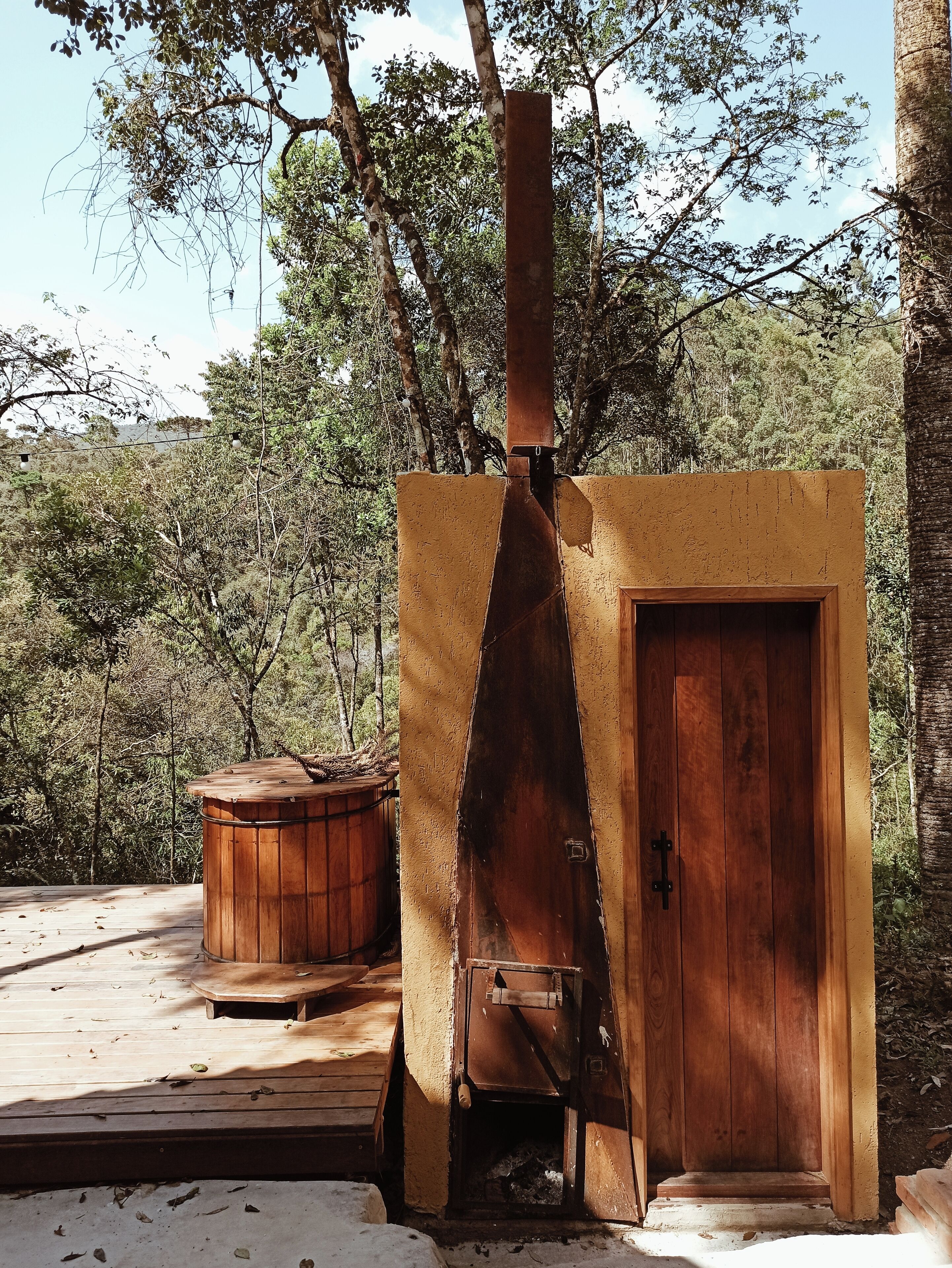 A rustic wooden structure with a chimney, a door, and a small wooden bench.