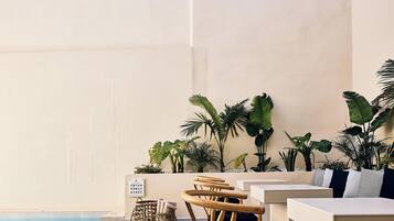 Un espace aménagé au bord de la piscine, avec des sièges, des plantes et un panneau de commande.