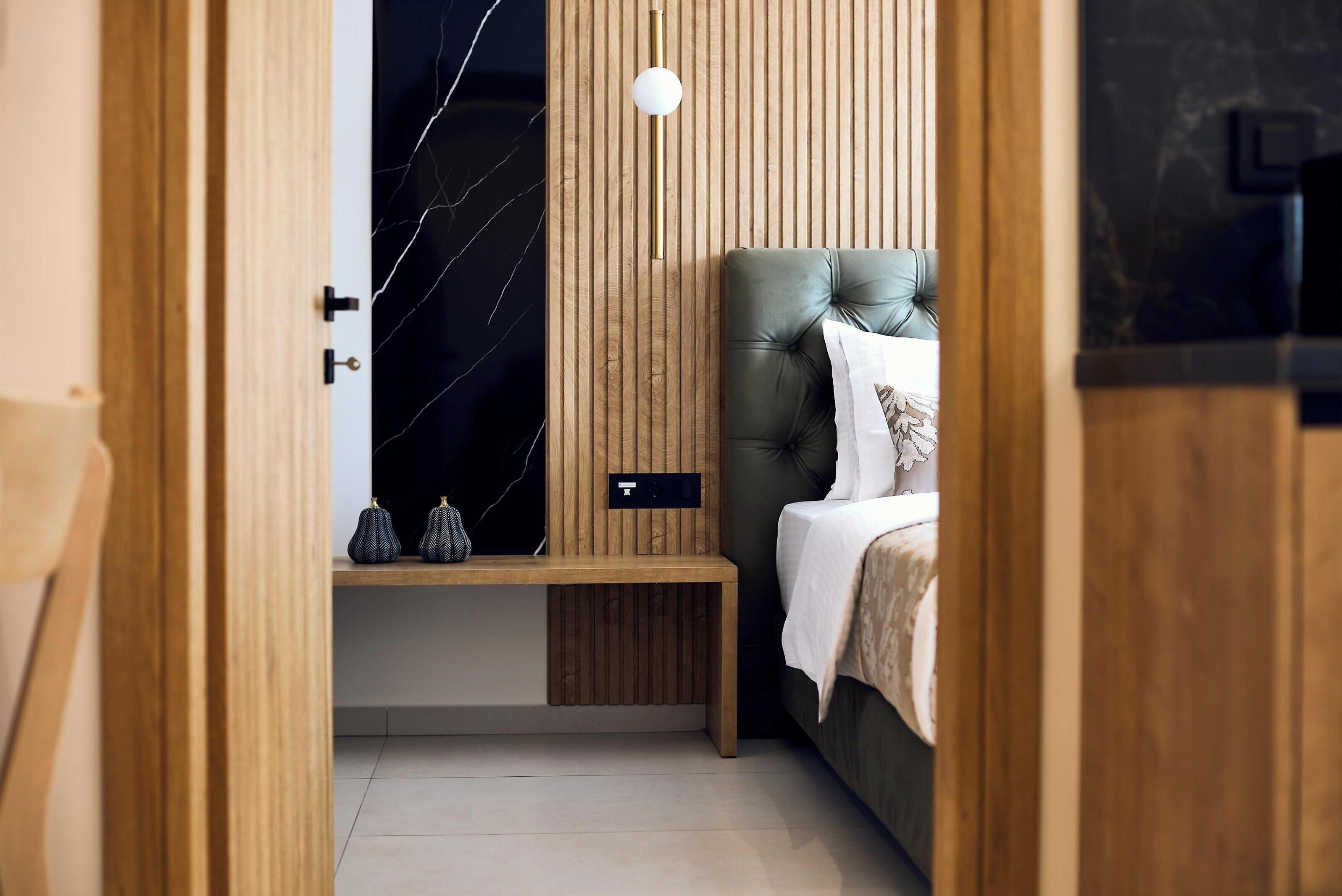 Un dormitorio moderno con cabecera de madera, una mesita de noche y una lámpara de pared.