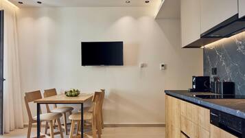 Eine moderne Küche mit Wand-Fernseher, einem Holzespeisetisch mit Stühlen und integrierten Geräten.